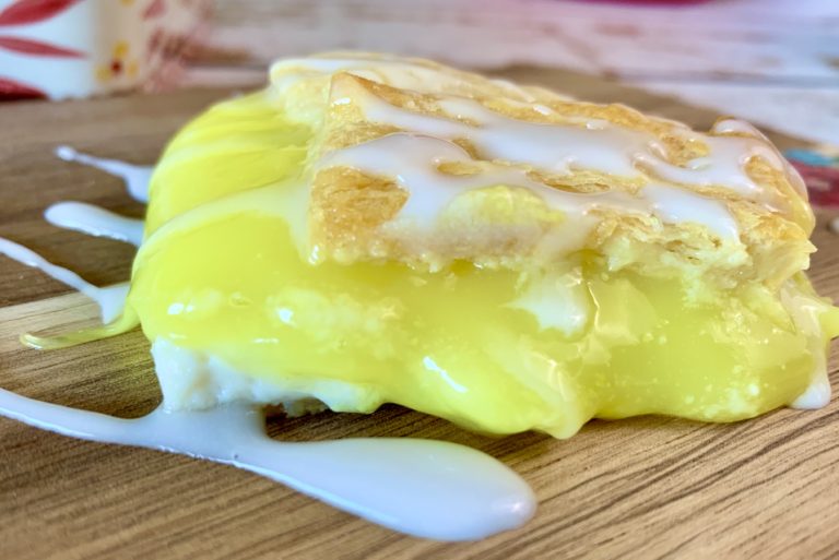 close up of a lemon pie bar and sugar glaze on a cutting board