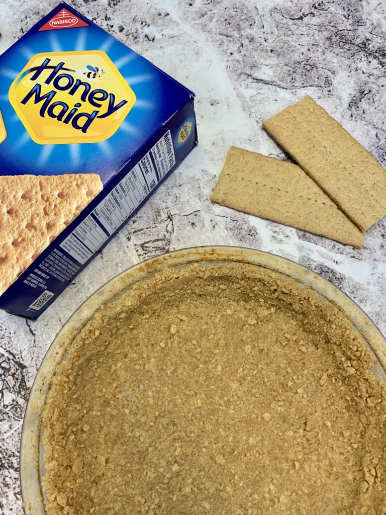 box of Honey Maid graham crackers and Pyrex pie pan with a graham cracker crust in it