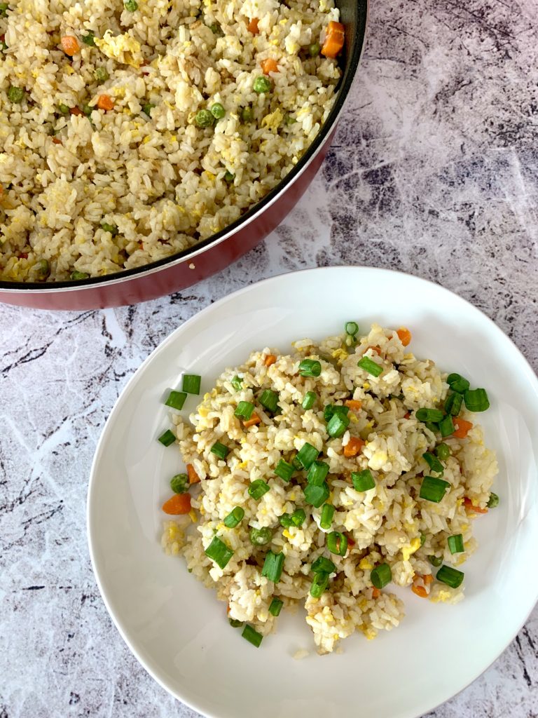 fried rice in a white plate and a large skillet