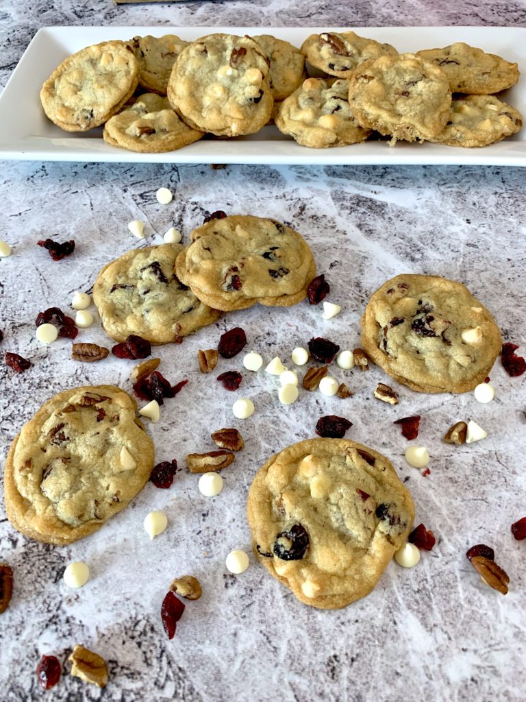 cranberry white chocolate chip pecan cookies on a white plate and marble table