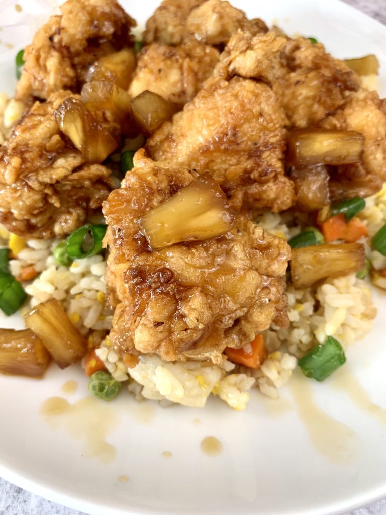 fried chicken with white rice, peas and carrots on a white plate