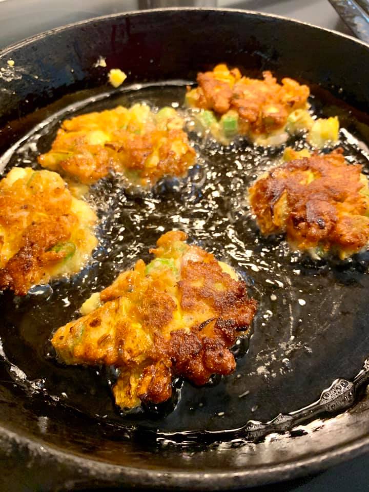 frying okra fritters in a large skillet