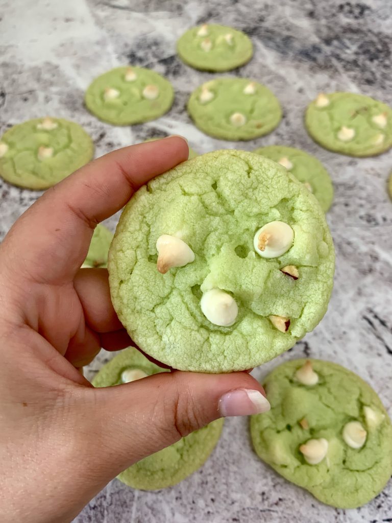 hand holding a pistachio white chocolate chip cookie