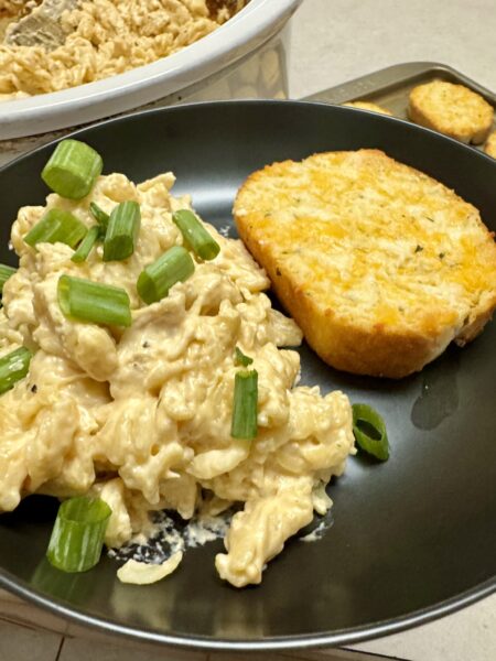chicken pasta and garlic bread on a black plate