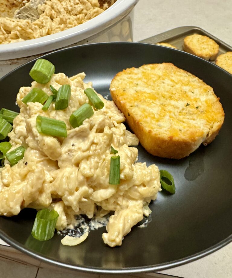 chicken pasta and garlic bread on a black plate
