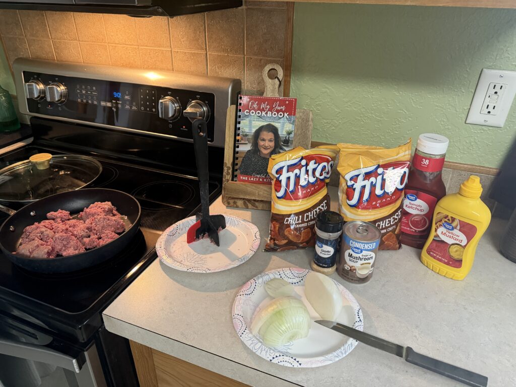 Picture of ground beef cooking in a skillet and chopping onion on a paper plate