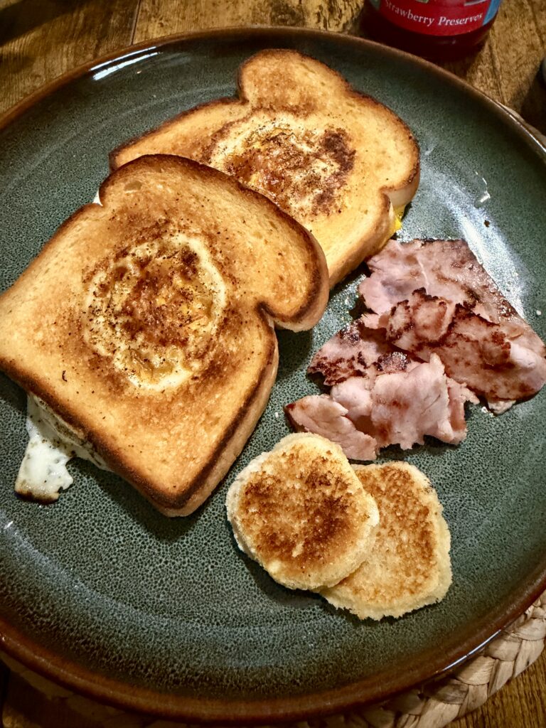 Picture of egg in a basket of toast on a green plate