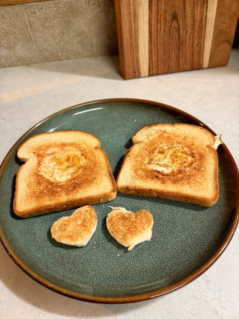 Picture of egg in a basket of toast on a green plate