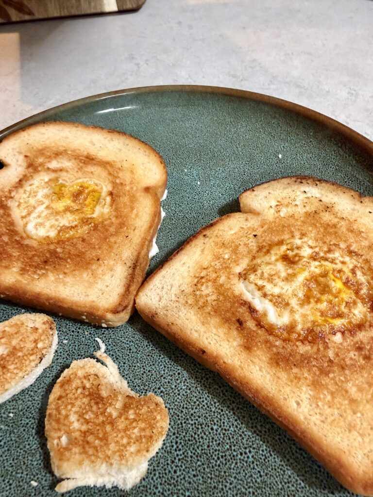 Picture of egg in a basket of toast on a green plate