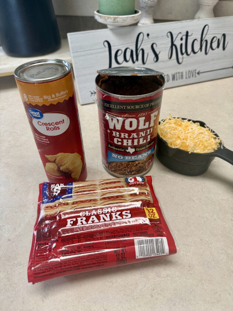 Picture of a the ingredients for a 4 ingredient chili cheese hotdog bake in a white baking dish.