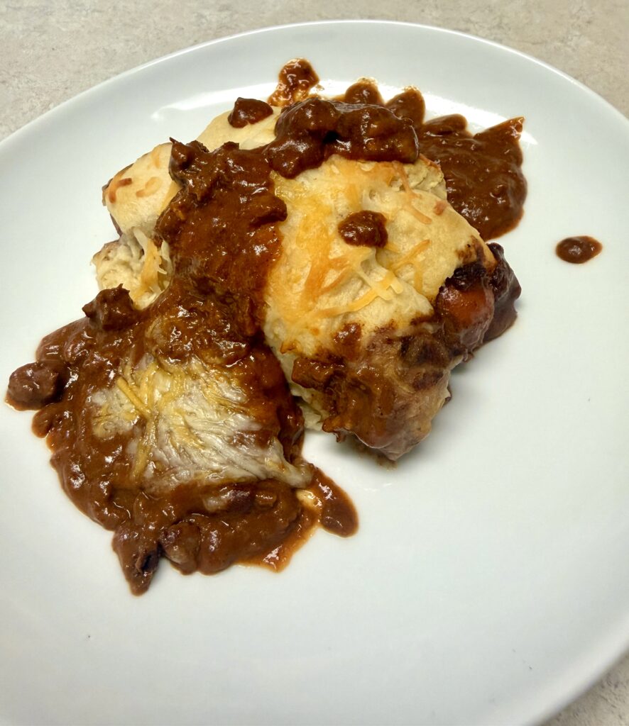 Picture of a 4 ingredient chili cheese hotdog bake in a white baking dish.
