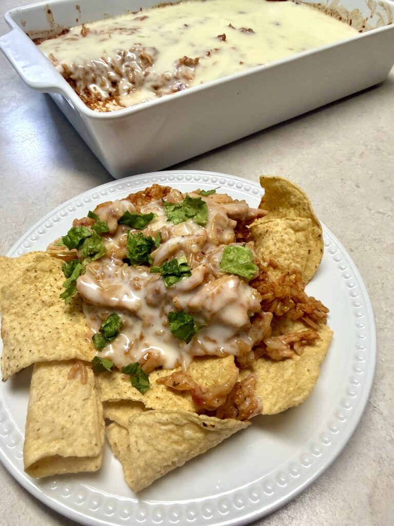 Picture of chicken fajita queso bake on a white plate and in a white baking dish.