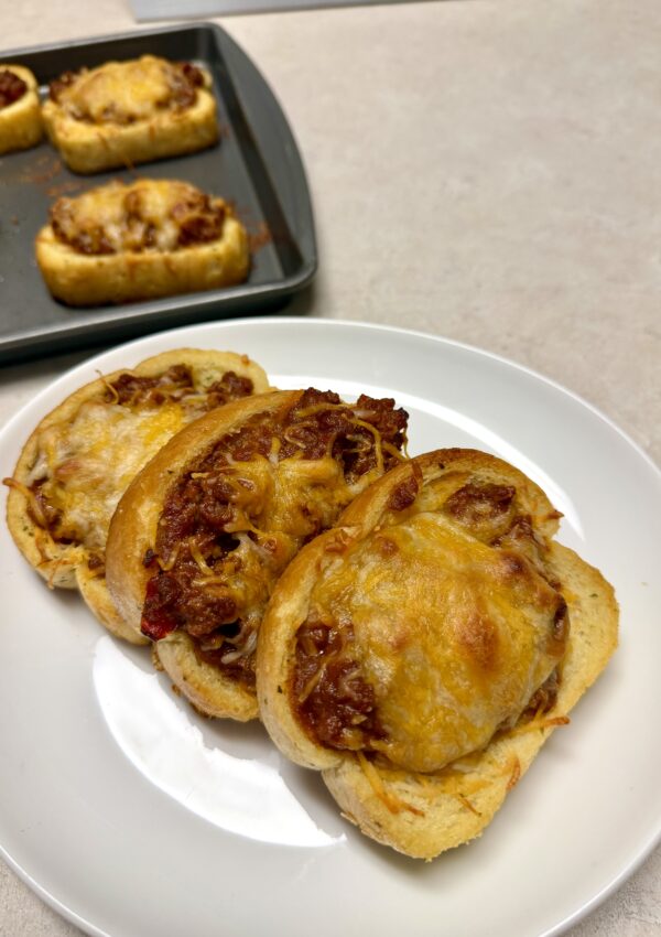 Picture of 4 ingredient Texas toast sloppy joes on a white plate and a baking sheet pan.