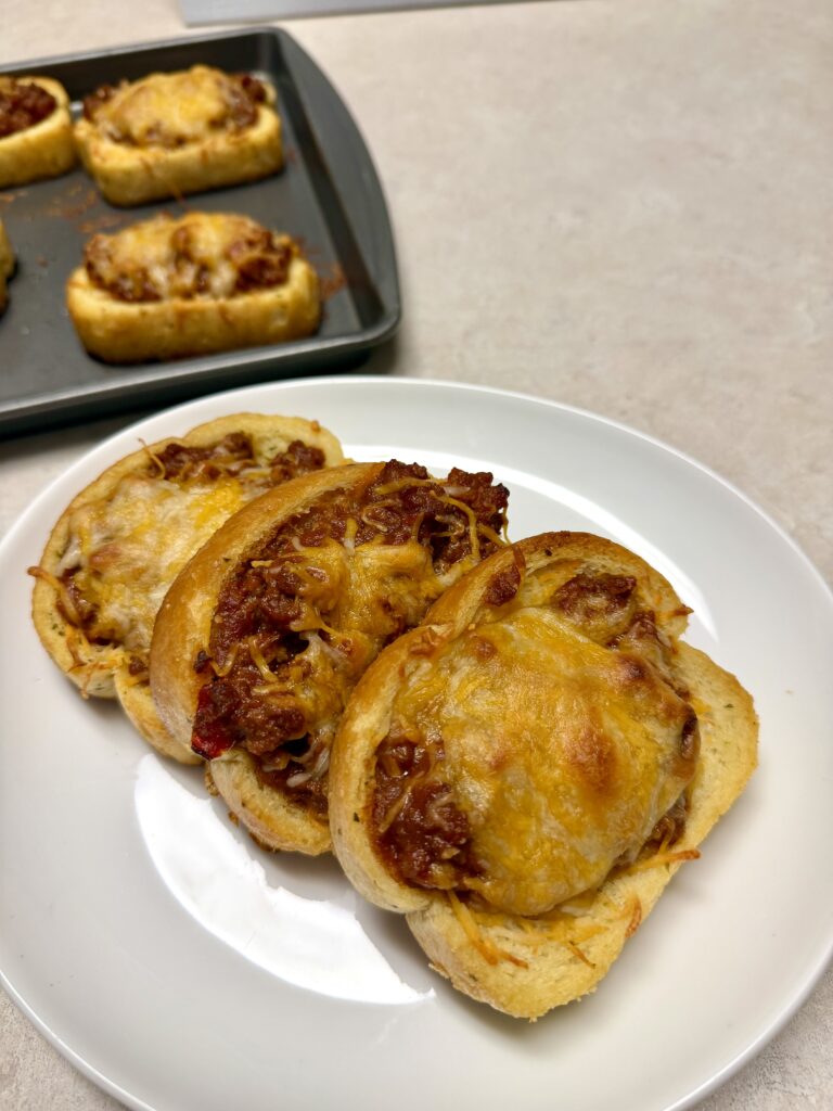 Picture of 4 ingredient Texas toast sloppy joes on a white dish and a baking sheet pan.