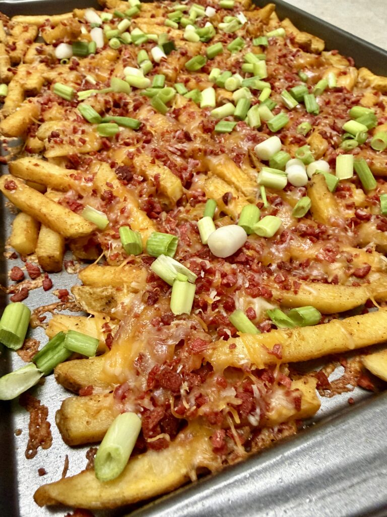 loaded bacon cheese fries on a baking sheet