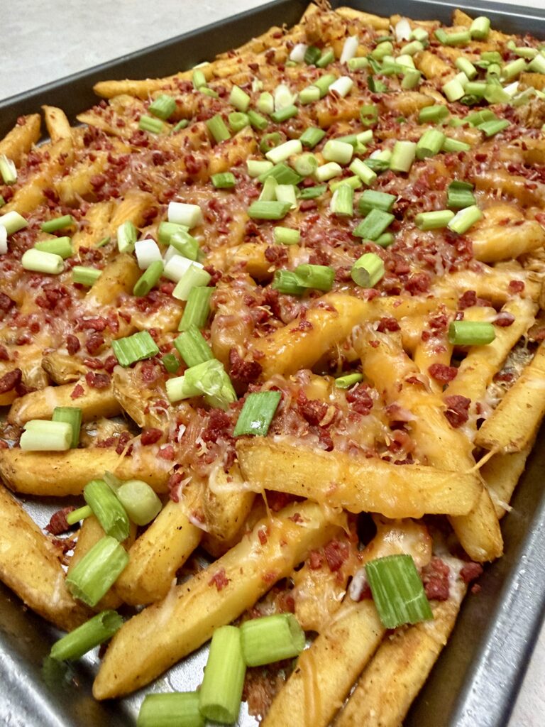 loaded bacon cheese fries on a baking sheet