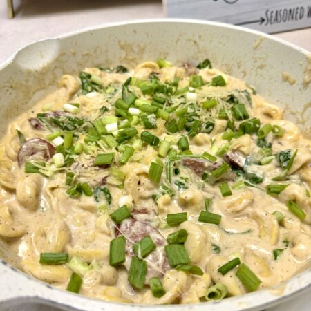 smoked sausage tortellini alfredo in a white skillet